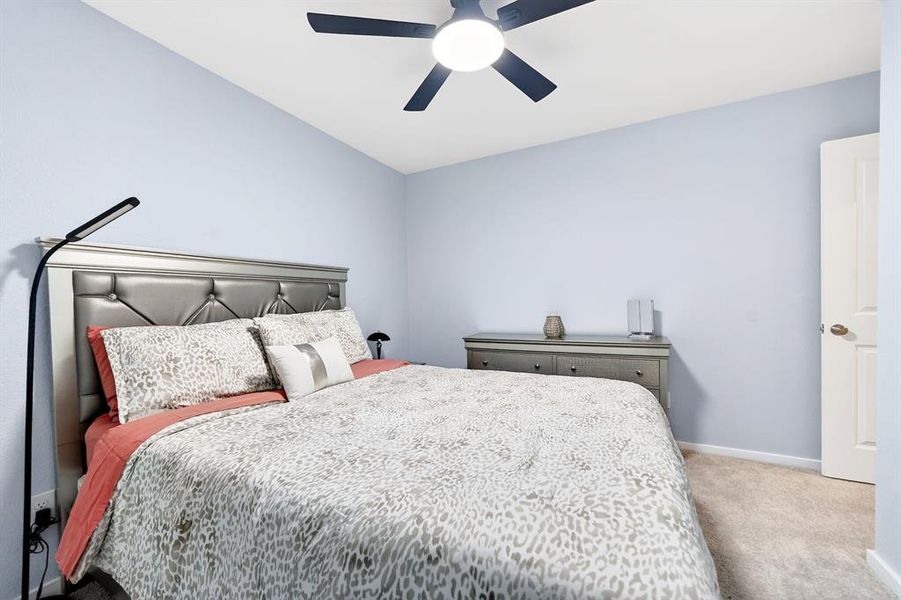 Bedroom featuring light blue walls, a ceiling fan with integrated lighting, and carpet flooring