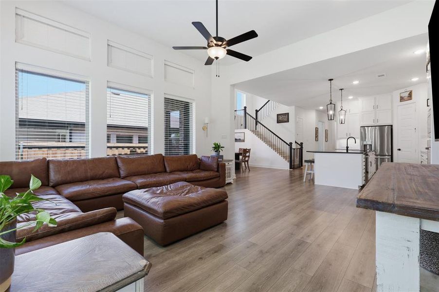Open-concept living space featuring wood-finish flooring, high ceilings, and an integrated kitchen Open-concept living space featuring wood-finish flooring, high ceilings, and an integrated kitchen