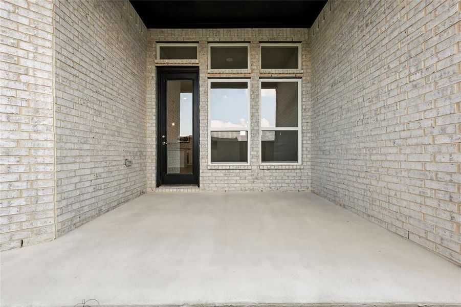 Doorway to property with brick siding and a patio