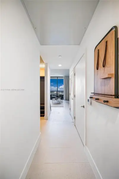 Hallway featuring oversized tile flooring, recessed ceiling lighting, and smooth-finish walls