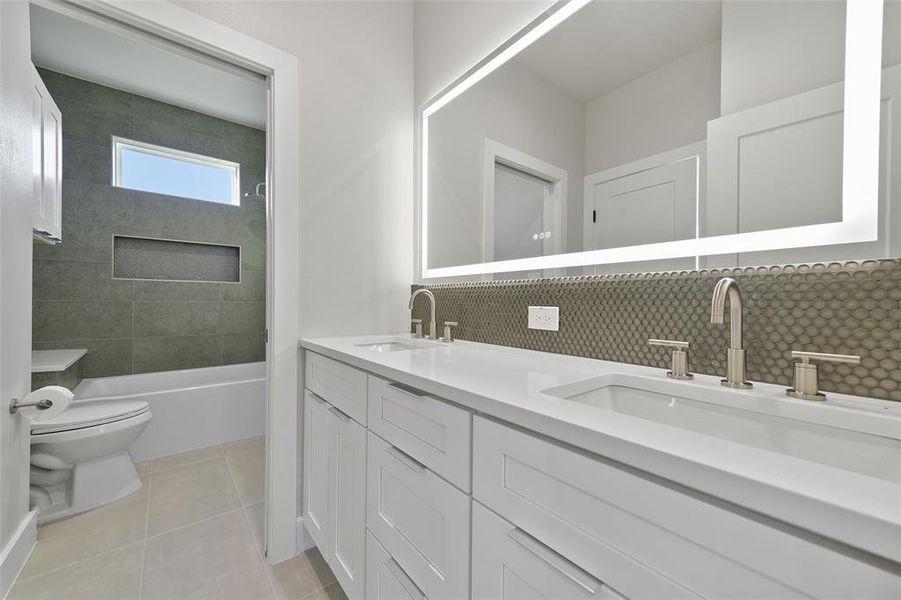 Full bathroom with toilet, tiled shower / bath combo, tasteful backsplash, tile patterned flooring, and vanity