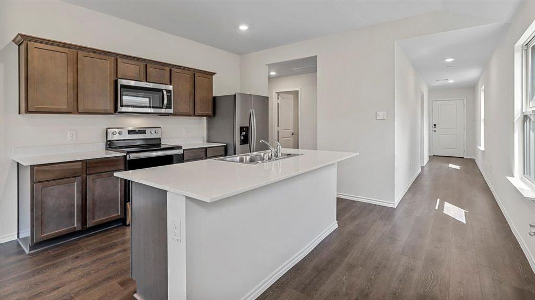 Kitchen with stainless steel appliances, a kitchen island with sink, recessed lighting, dark wood-type flooring, and dark wood finish cabinets Kitchen with stainless steel appliances, a kitchen island with sink, recessed lighting, dark wood-type flooring, and dark wood finish cabinets
