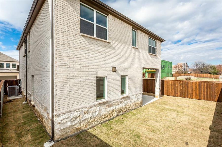 View of side of property with central air condition unit, a patio area, and a yard