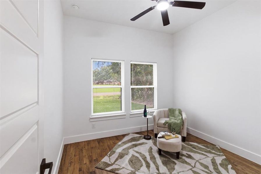 Room featuring wood-finish flooring, white baseboards, and two large windows