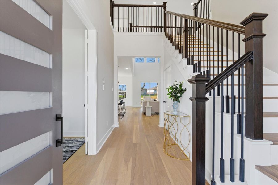 As you enter the home, you’re welcomed by beautiful hardwood flooring and high 21-foot ceilings, creating a bright and open first impression. To the right, the staircase leads to the second floor.