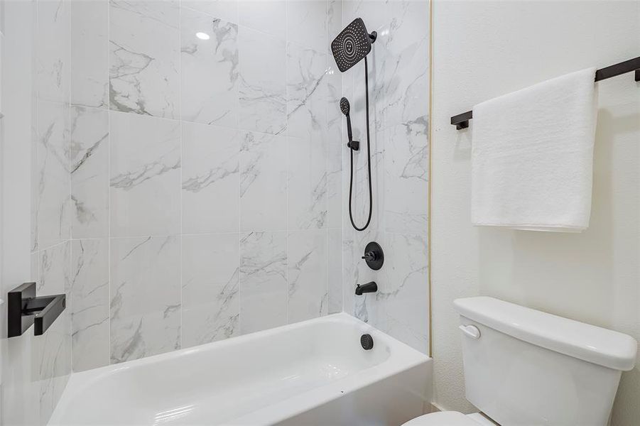 Bathroom with tiled shower / bath combo and toilet