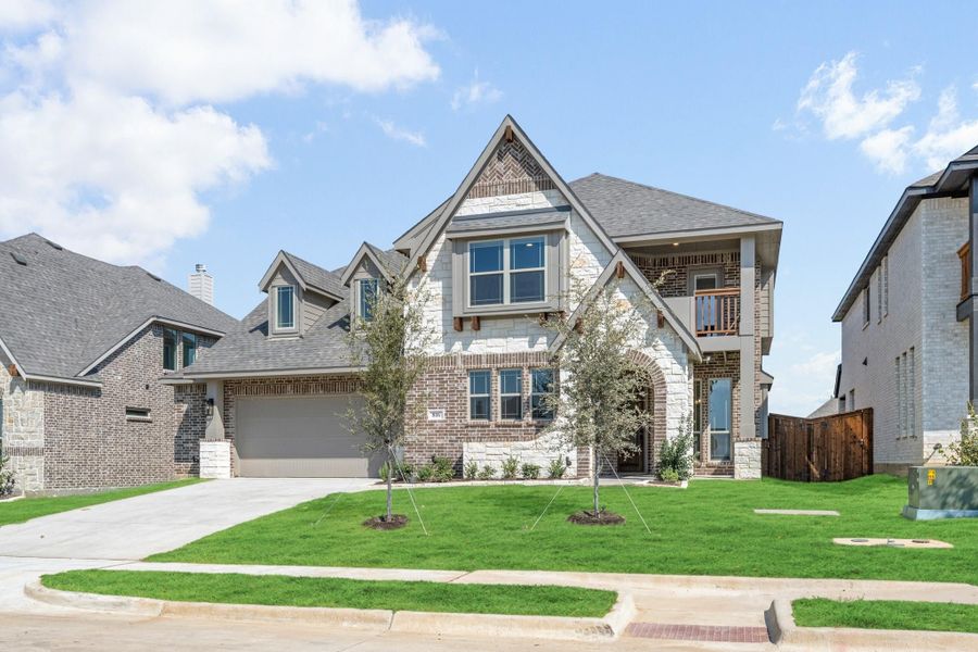 Two-story brick and stone home with two-car garage, arched entry, and manicured front lawn