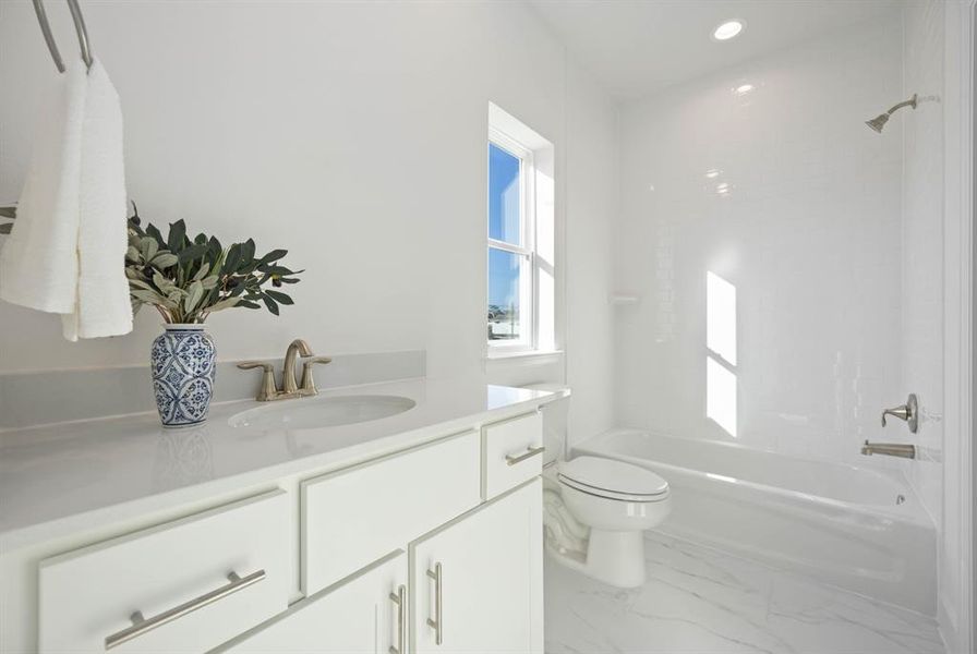 This Jack and Jill bathroom between two secondary bedrooms features neutral finishes, offering a serene, shared space.