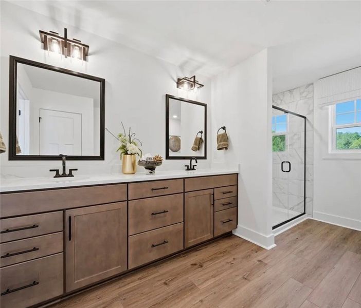 A well-lit primary bathroom features a double vani A well-lit primary bathroom features a double vani