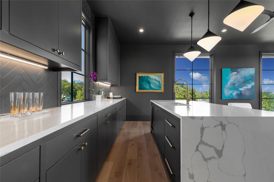 Kitchen featuring decorative backsplash, light wood-style flooring, recessed lighting, hanging light fixtures, and light stone countertops Kitchen featuring decorative backsplash, light wood-style flooring, recessed lighting, hanging light fixtures, and light stone countertops