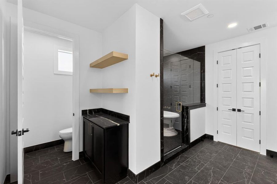 Primary bathroom featuring a closet, dark marble finish flooring, a stall shower, and recessed lighting
