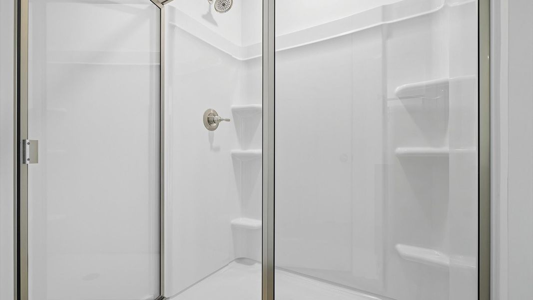 Spacious and modern primary bathroom with walk-in shower and good lighting by DRB Homes Spacious and modern primary bathroom with walk-in shower and good lighting by DRB Homes