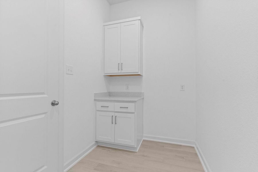 Convenient utility room with built-in cabinetry, perfect for storage and organization to keep laundry essentials neatly tucked away.  Room area for that freezer you always wanted to keep in your home.