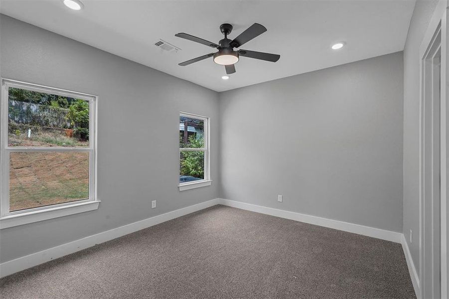 Empty room with a healthy amount of sunlight, ceiling fan, and carpet flooring