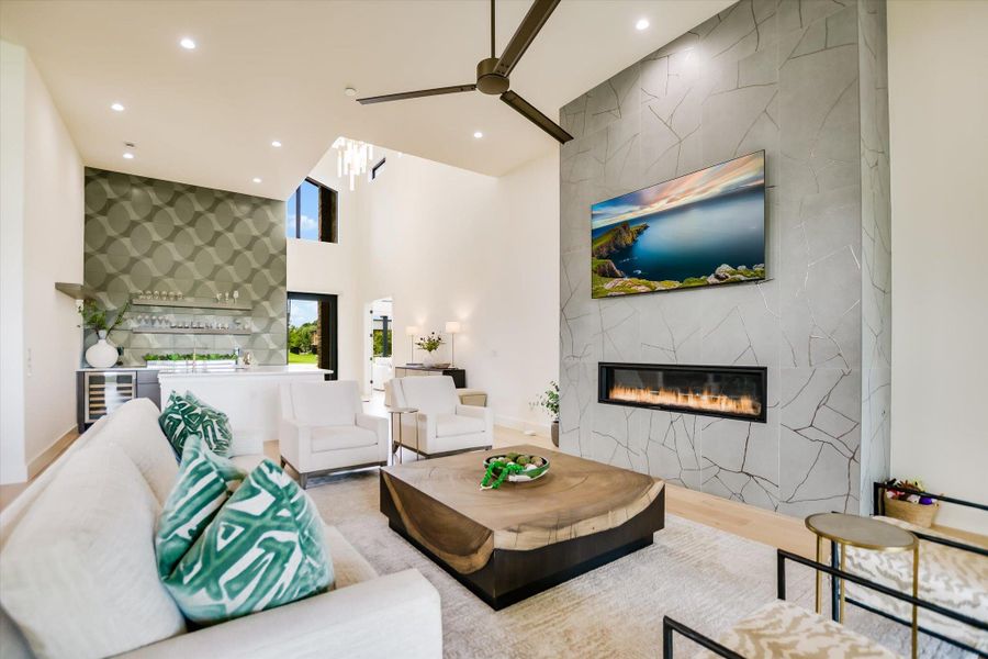 A striking fireplace with a sleek hearth anchors this grand living area with soaring ceilings.