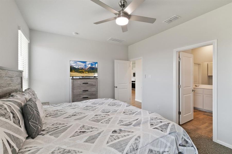 Bedroom featuring ceiling fan, light colored carpet, and ensuite bath