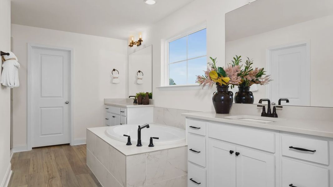 Stonefield home plan en suite primary bath with separate vanities, soaking tub and tile shower Stonefield home plan en suite primary bath with separate vanities, soaking tub and tile shower