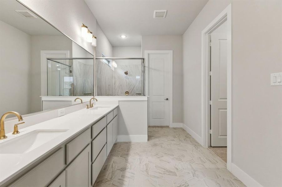 Bathroom featuring a marble finish shower, double vanity, and marble look tiles