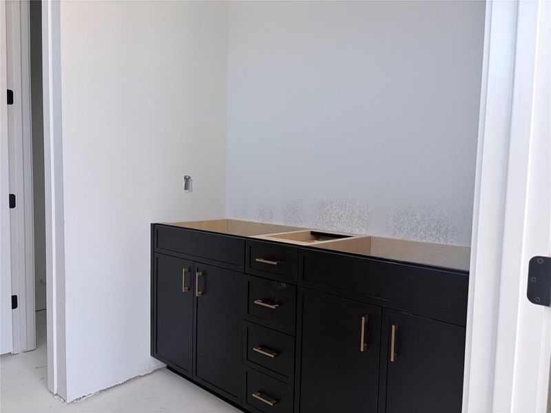 A well-appointed vanity with dark cabinetry and elegant hardware awaits its final touches. A well-appointed vanity with dark cabinetry and elegant hardware awaits its final touches.