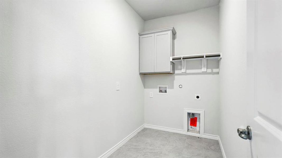 Utility room featuring gray wall cabinetry, open shelving, tile flooring, and light gray walls