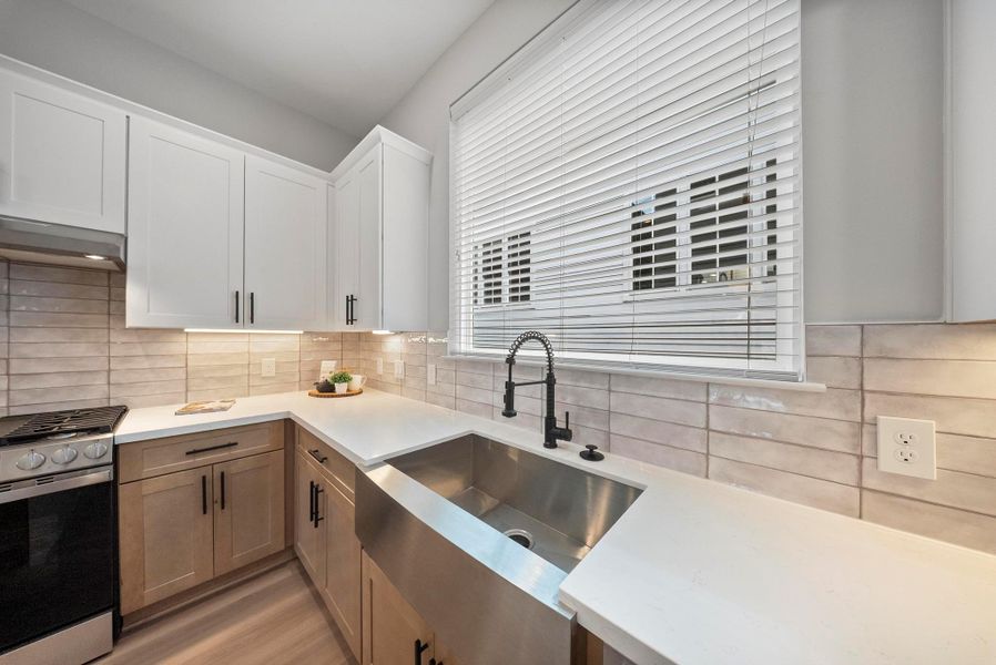 Modern kitchen featuring a spacious island with seating, elegant pendant lighting, and white cabinetry. Stainless steel appliances and a neutral color palette create a sleek, inviting atmosphere.