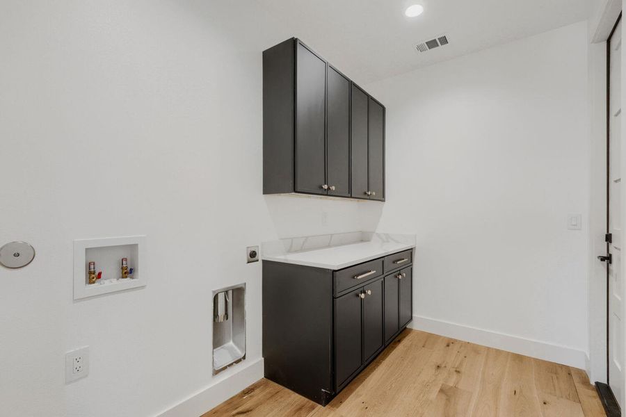 Laundry area featuring cabinet space, light wood finished floors, hookup for a washing machine, hookup for an electric dryer, and recessed lighting Laundry area featuring cabinet space, light wood finished floors, hookup for a washing machine, hookup for an electric dryer, and recessed lighting