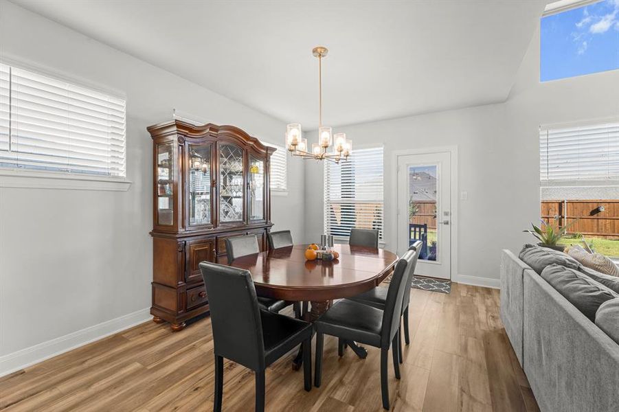 Dining space featuring wood finished floors, healthy amount of natural light, and a chandelier Dining space featuring wood finished floors, healthy amount of natural light, and a chandelier