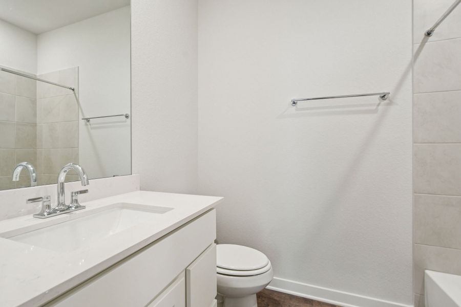 A bathroom with a sink toilet and mirror.