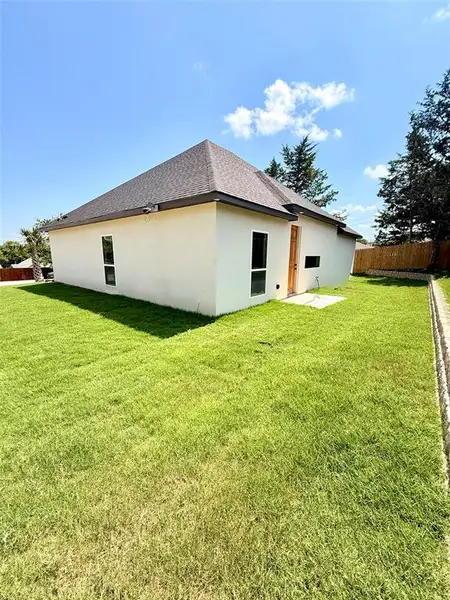 Back of house with stucco siding and a shingled roof