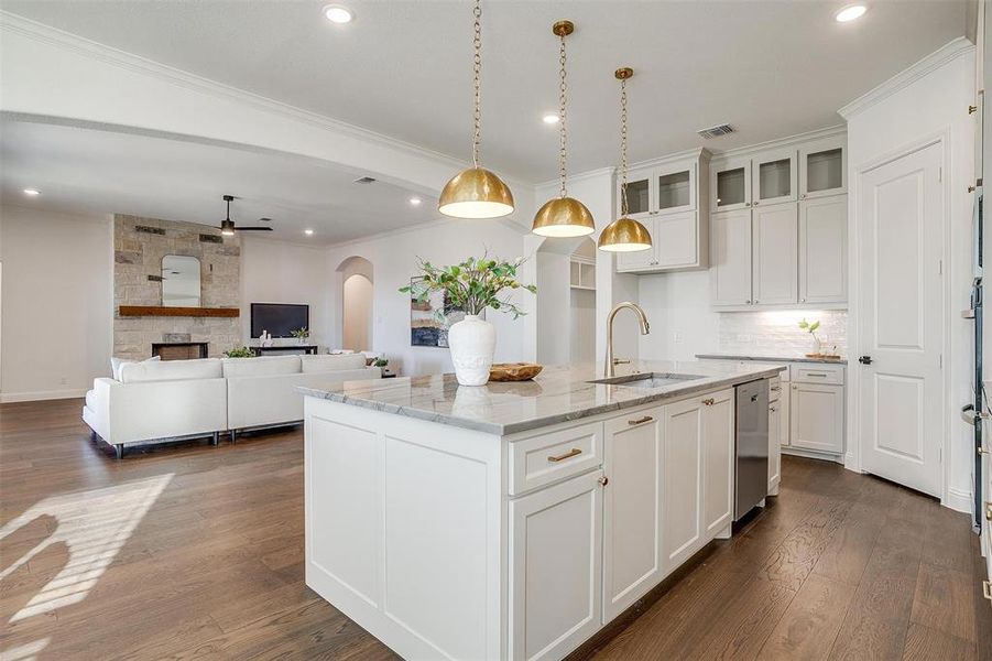 Kitchen featuring a large island, Quartzite countertops, gold hardware, decorative light fixtures, custom cabinetry to the ceiling, gas cooktop, double oven and walk in pantry