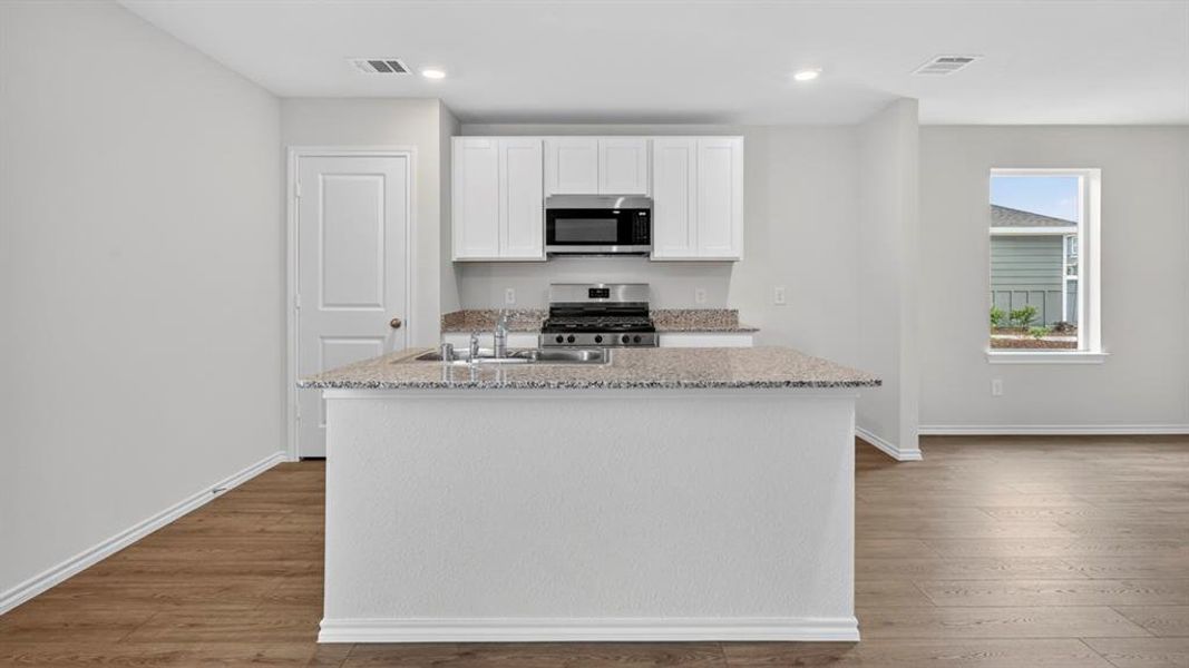 Kitchen island with a granite-style countertop and undermount sink