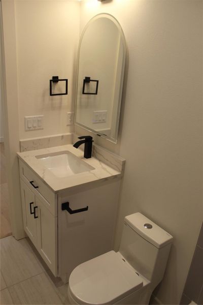 A refined bathroom featuring a contemporary vanity with a sleek faucet and a chic arched mirror.