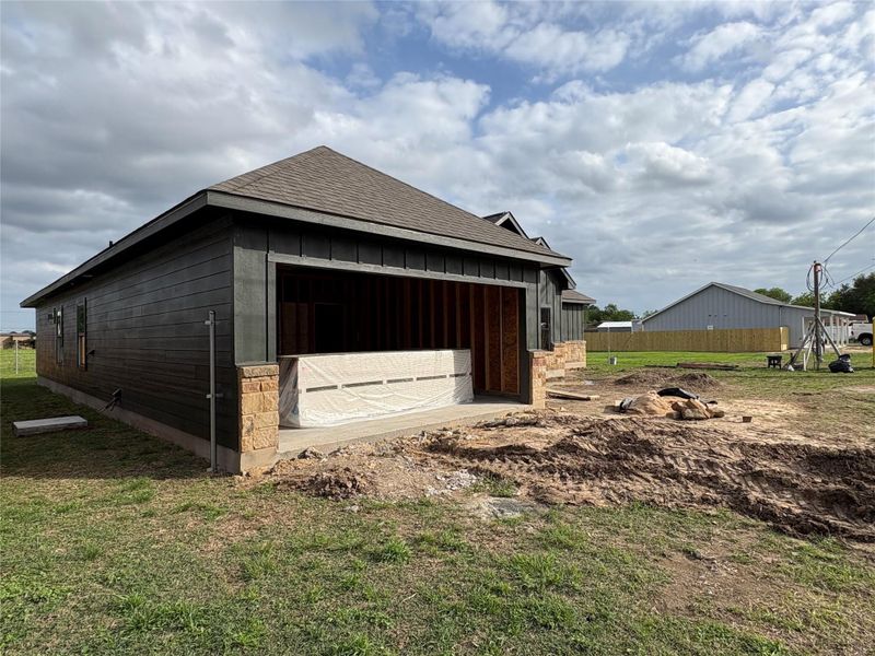 Side exterior featuring dark horizontal siding, stone accents