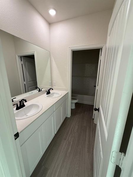 Jack & Jill Bathroom (upstairs) featuring wood finished floors, double vanity, and shower / tub combination Jack & Jill Bathroom (upstairs) featuring wood finished floors, double vanity, and shower / tub combination