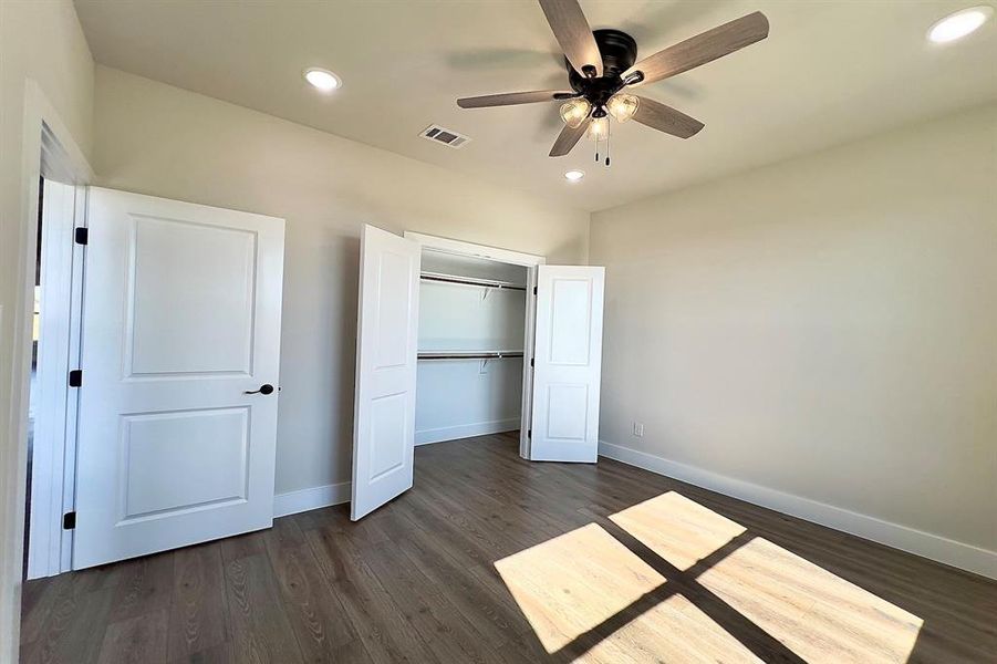 Unfurnished bedroom featuring recessed lighting, dark finished floors, ceiling fan, and a closet