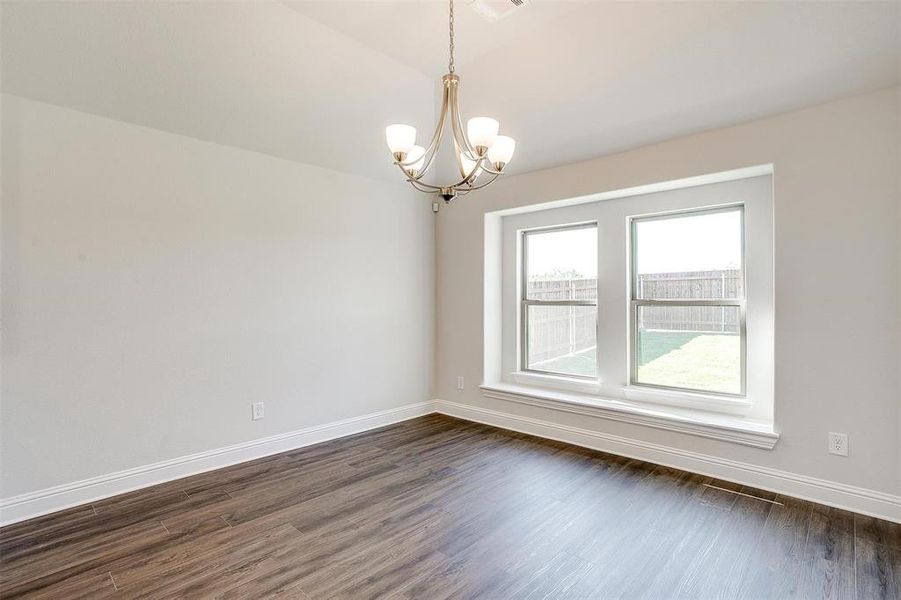 Spare room featuring dark wood-type flooring and a notable chandelier