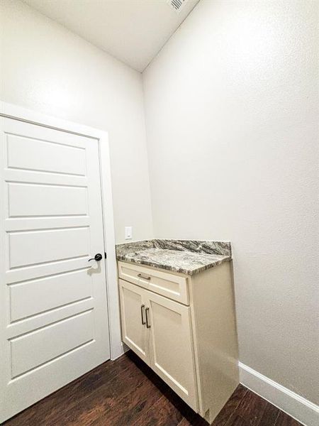 Laundry area with dark wood-style flooring and baseboards Laundry area with dark wood-style flooring and baseboards