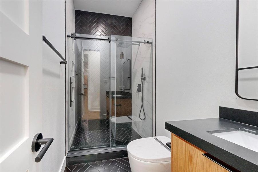 Bathroom with vanity, a shower with shower door, toilet, and tile patterned floors