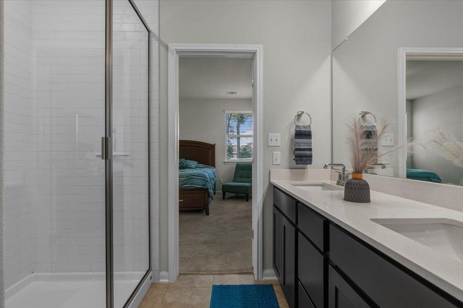 A contemporary bathroom features a double vanity and a glass-enclosed walk-in shower.