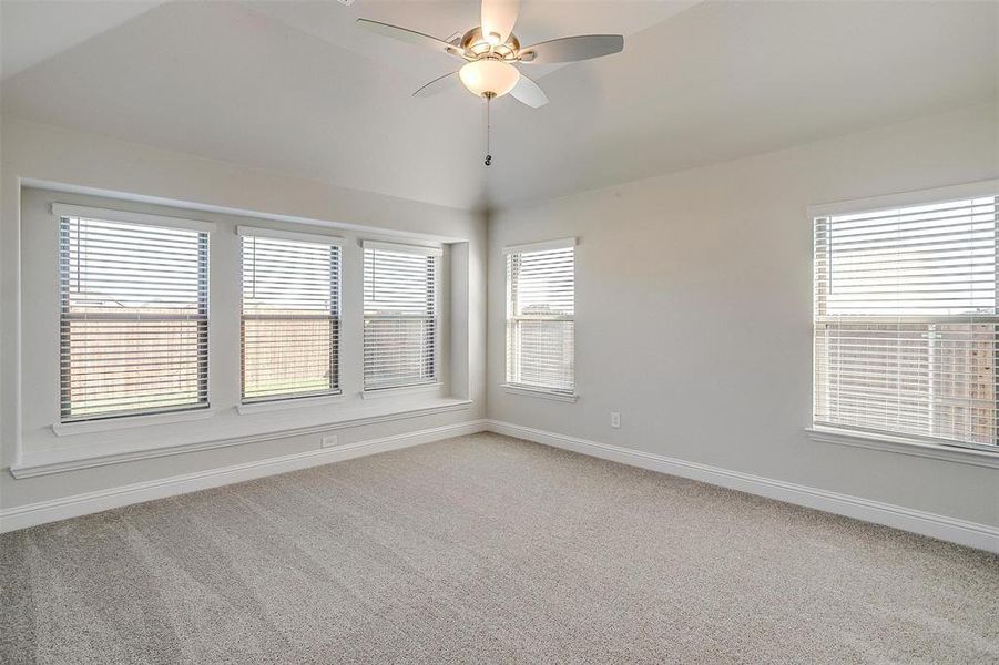 Empty room featuring carpet flooring, vaulted ceiling, and ceiling fan