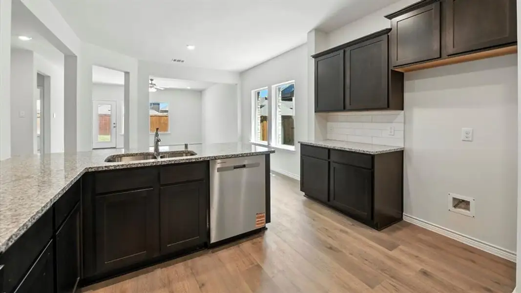 Kitchen featuring light stone counters, dishwasher, decorative backsplash, light wood-style floors, and a ceiling fan