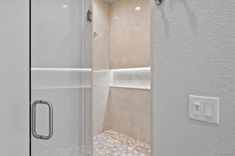 The large, zero-threshold shower is amazing, showcasing dual shower heads, a handheld faucet, built-in bench, plus a dimmable lighted shelf.