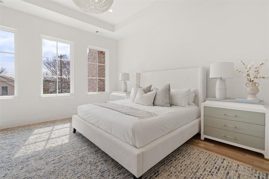 Bedroom featuring recessed lighting, a raised ceiling, visible vents, wood finished floors, and baseboards