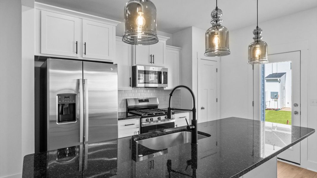 Tasteful design meets functional luxury in this kitchen with a 9-foot island and modern pendant lighting Tasteful design meets functional luxury in this kitchen with a 9-foot island and modern pendant lighting