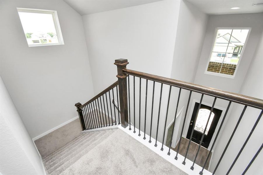 Ascend upstairs to openness: The modern and dark rail stains, coupled with sleek metal balusters, infuse this area with a spacious and contemporary ambiance. Sample photo of completed home with similar floor plan. As-built interior colors and selections may vary.