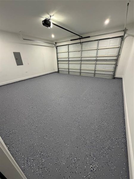 Spacious garage featuring a durable flake epoxy flooring, crisp white walls, recessed lighting, an automatic garage door opener, and a panel box Spacious garage featuring a durable flake epoxy flooring, crisp white walls, recessed lighting, an automatic garage door opener, and a panel box