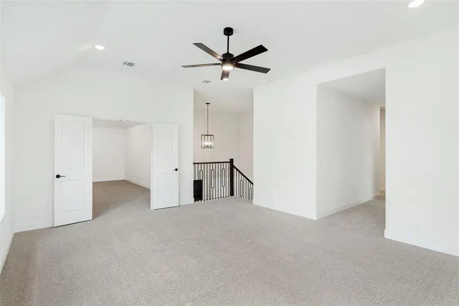 Spacious upstairs bonus room with carpet, ceiling fan, vaulted ceiling, and staircase landing nearby.