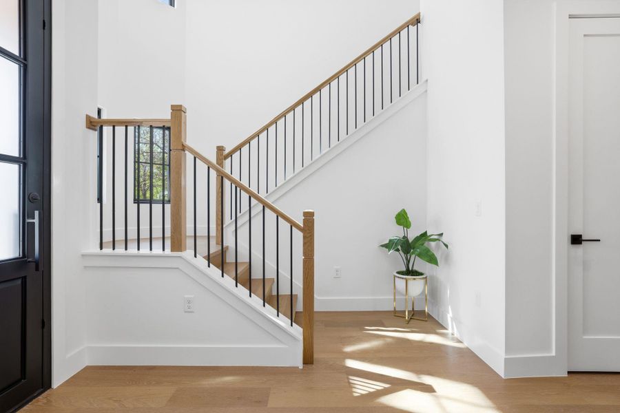 Entryway featuring light wood finished floors, healthy amount of natural light, and a high ceiling