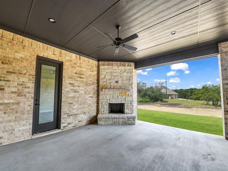 View of patio / terrace featuring an outdoor stone fireplace and ceiling fan