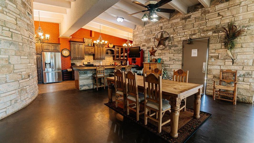 Dining space featuring a chandelier, a ceiling fan, and finished concrete flooring